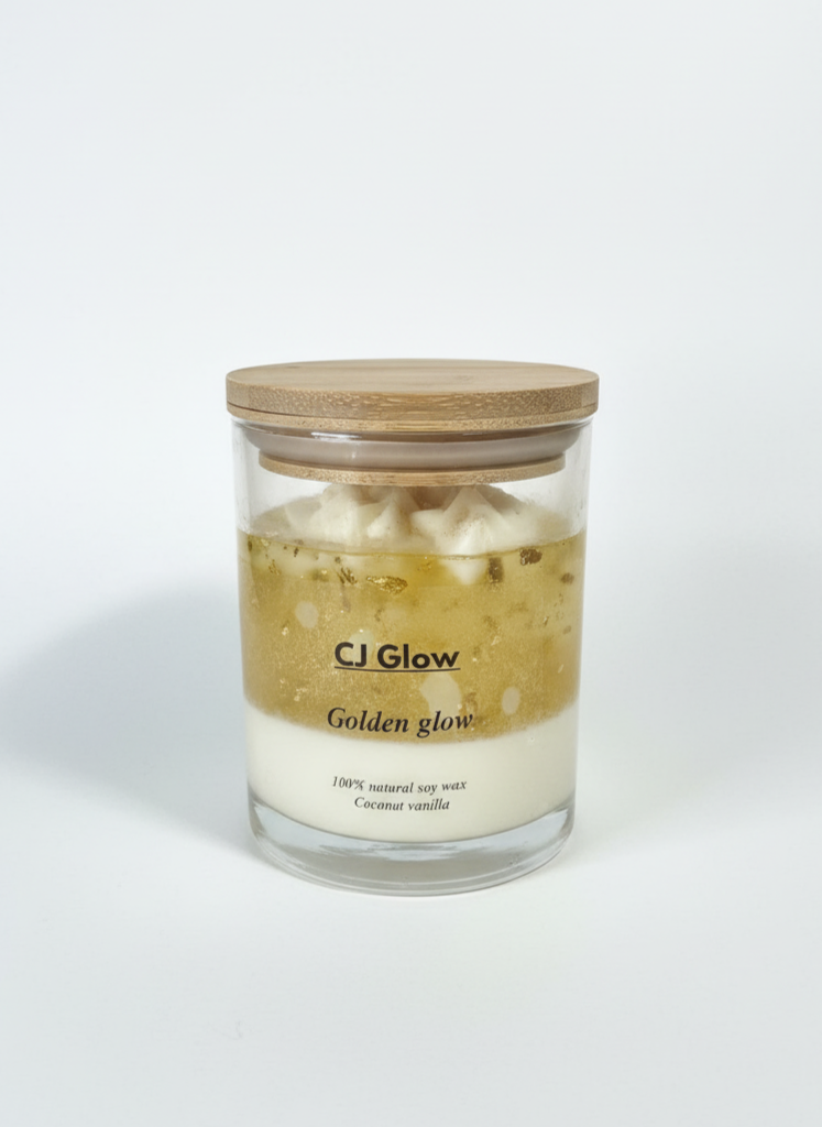 Glass candle with wooden lid labeled 'CJ Glow Golden glow' on a white background