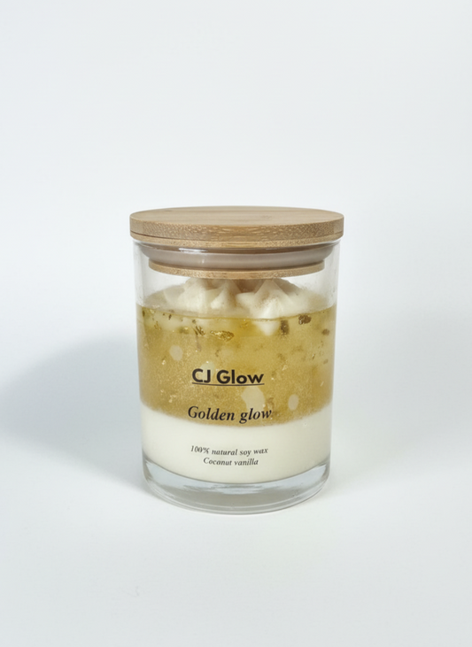 Glass candle with wooden lid labeled 'CJ Glow Golden glow' on a white background
